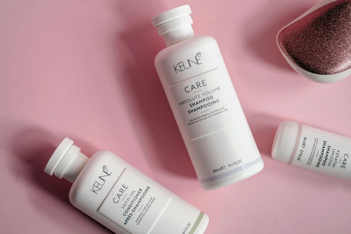 Elegant flat lay of shampoo and conditioner bottles on pink background, ideal for beauty brands.